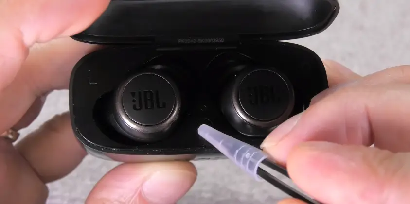 Pressing the button inside the case of JBL earbuds.